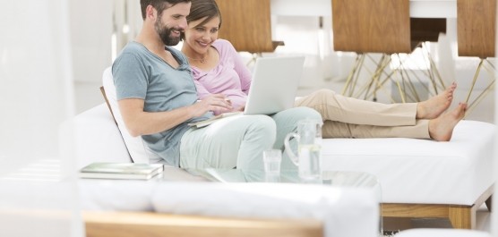 Image d'un couple assis sur un canapé faisant une recherche sur tablette dans un salon