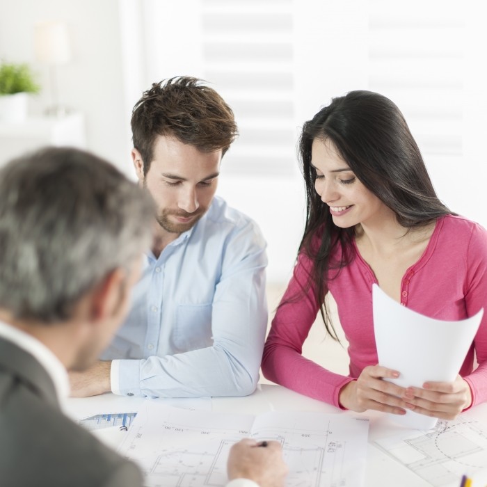 Image d'un couple se faisant conseiller par un professionel dans un bureau